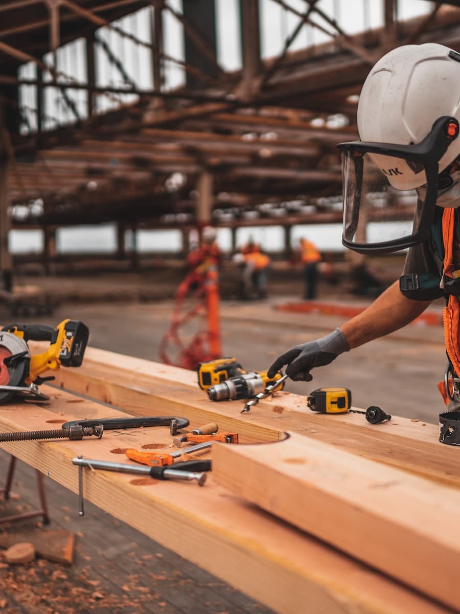 Tradesman using a power tool on a large timber beam