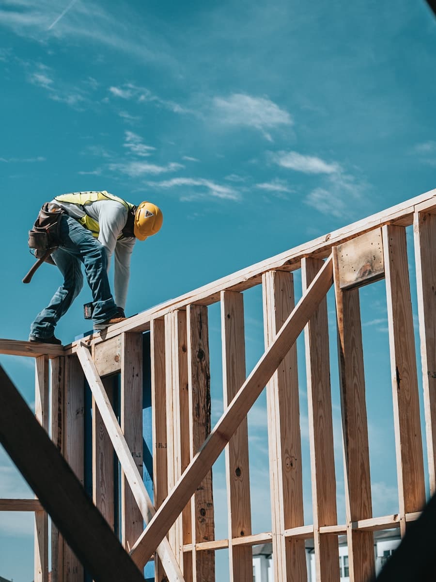 Carpenter in a hard hat working on timber wall framing