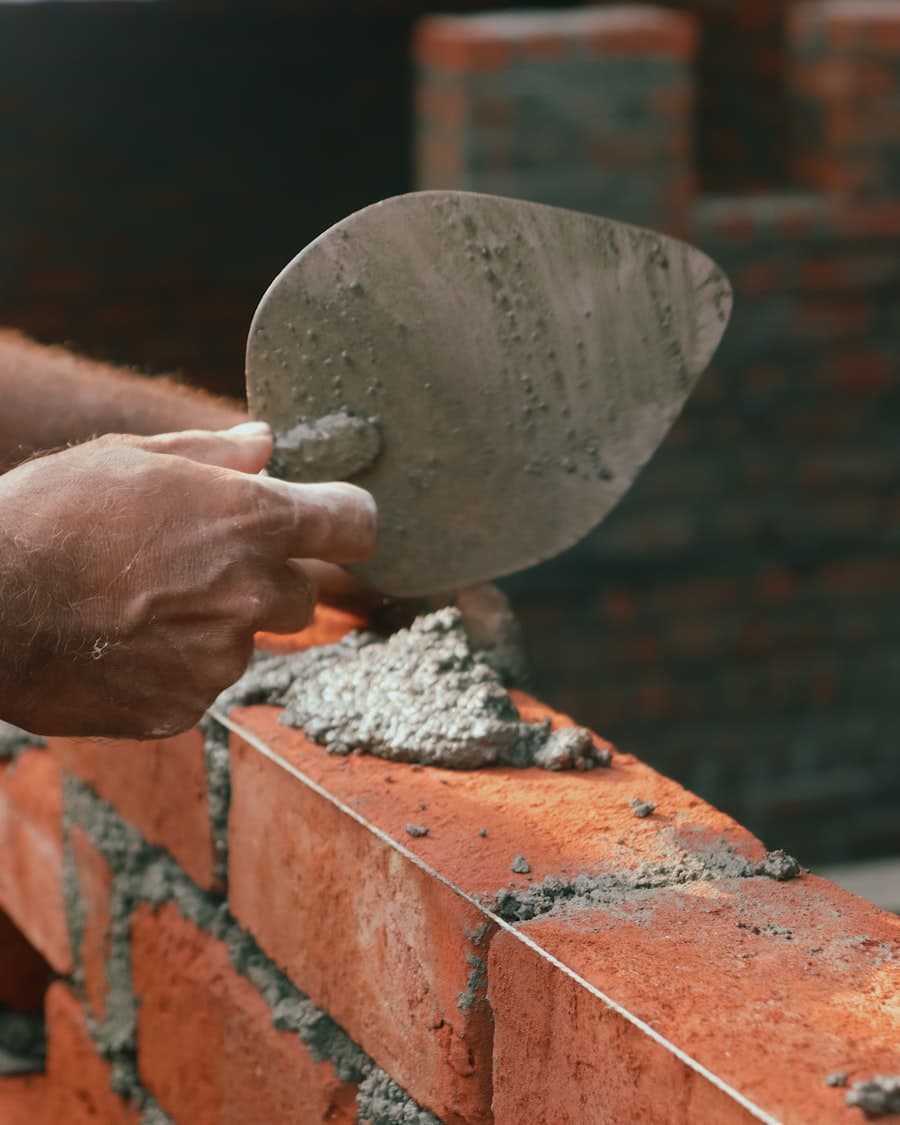 Mason spreading mortar with a trowel while laying brick