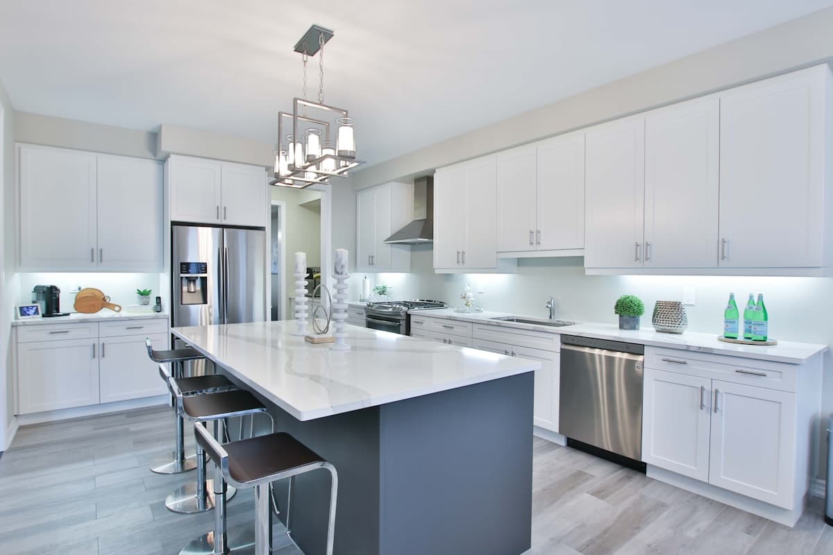 Finished white shaker kitchen with a quartz waterfall island and stainless appliances