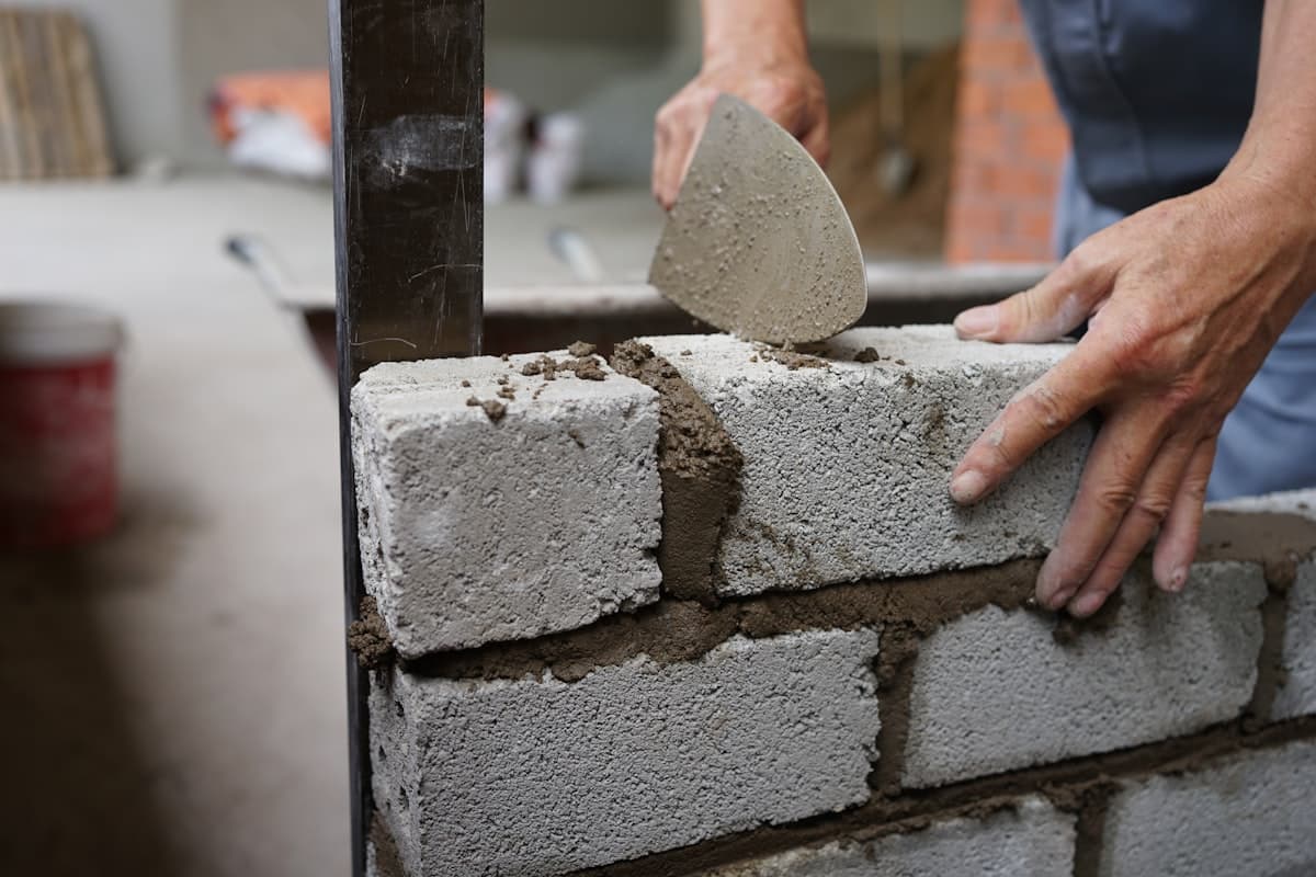 Mason spreading mortar while laying a concrete block wall